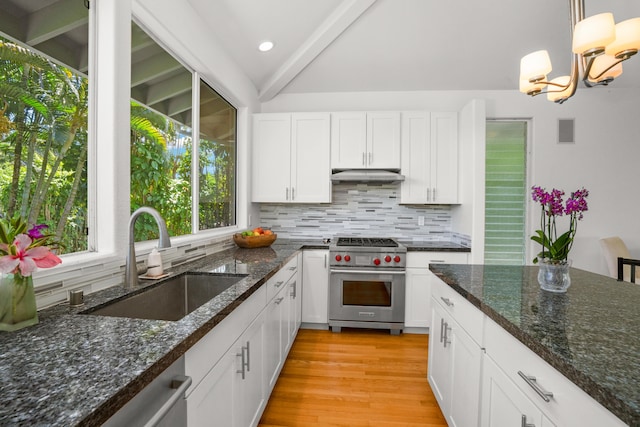 kitchen featuring under cabinet range hood, stainless steel appliances, a sink, white cabinets, and decorative light fixtures