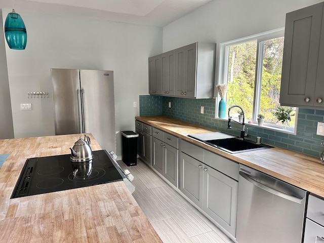 kitchen with appliances with stainless steel finishes, tasteful backsplash, sink, wood counters, and gray cabinets