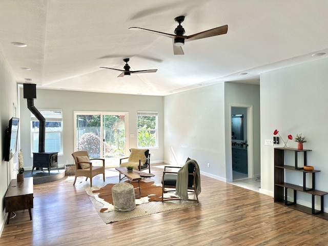 living room with ceiling fan, hardwood / wood-style flooring, and a wood stove