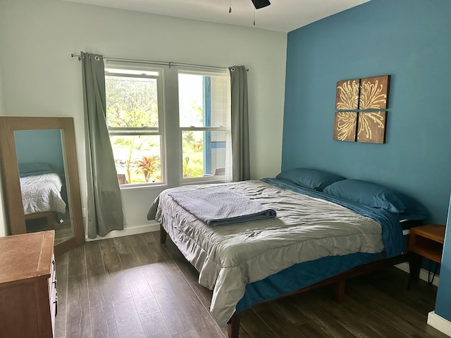 bedroom featuring ceiling fan, dark wood-type flooring, and multiple windows