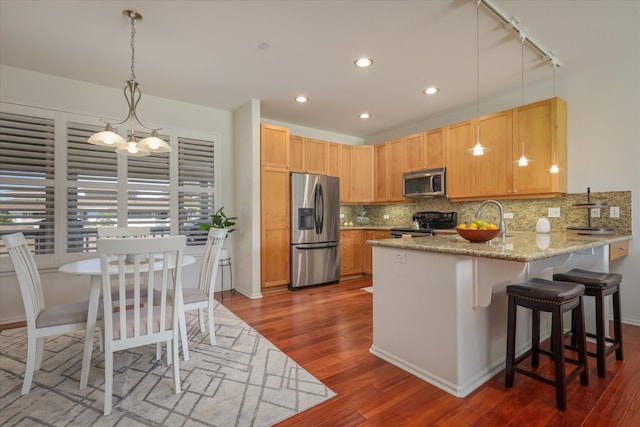 kitchen featuring decorative light fixtures, appliances with stainless steel finishes, dark hardwood / wood-style floors, kitchen peninsula, and decorative backsplash