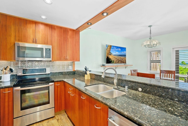 kitchen with a notable chandelier, decorative backsplash, sink, stainless steel appliances, and dark stone counters