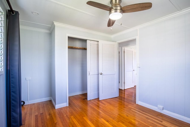 unfurnished bedroom featuring ceiling fan, wood-type flooring, a closet, and ornamental molding