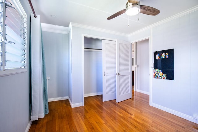 unfurnished bedroom featuring ceiling fan, crown molding, hardwood / wood-style flooring, and a closet