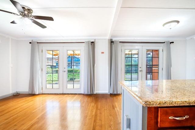 kitchen featuring beamed ceiling, crown molding, light hardwood / wood-style flooring, light stone countertops, and french doors