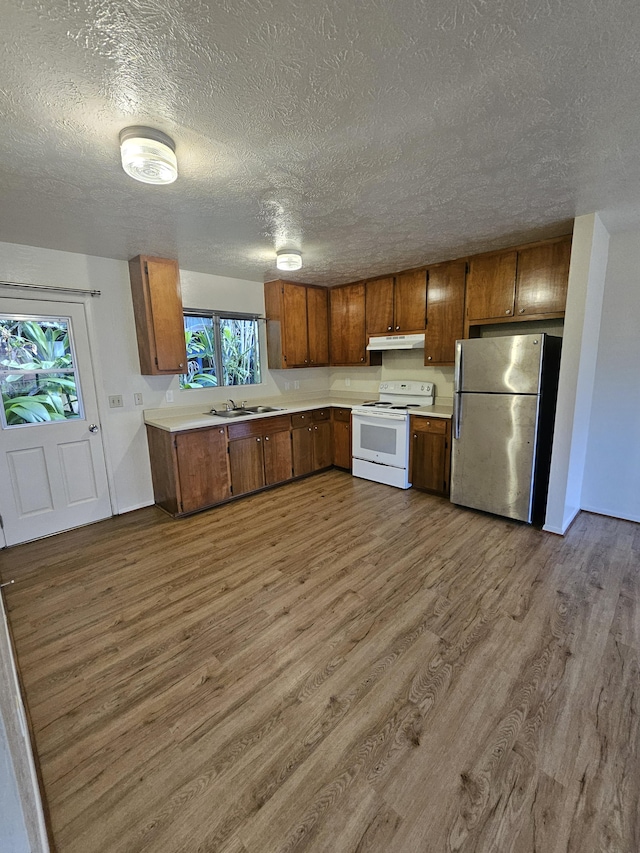 kitchen featuring hardwood / wood-style floors, stainless steel fridge, white electric range, a textured ceiling, and sink