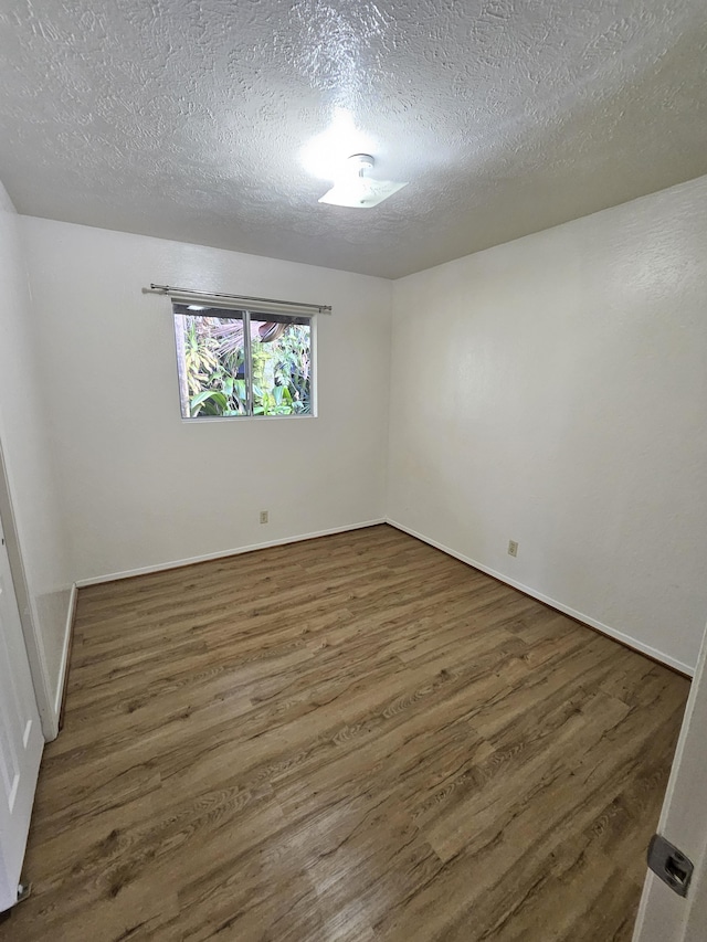 unfurnished room with dark wood-type flooring and a textured ceiling