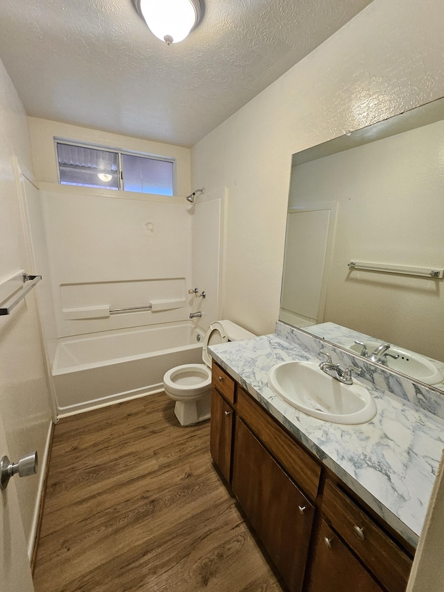 full bathroom featuring toilet, hardwood / wood-style flooring, a textured ceiling, shower / bathtub combination, and vanity