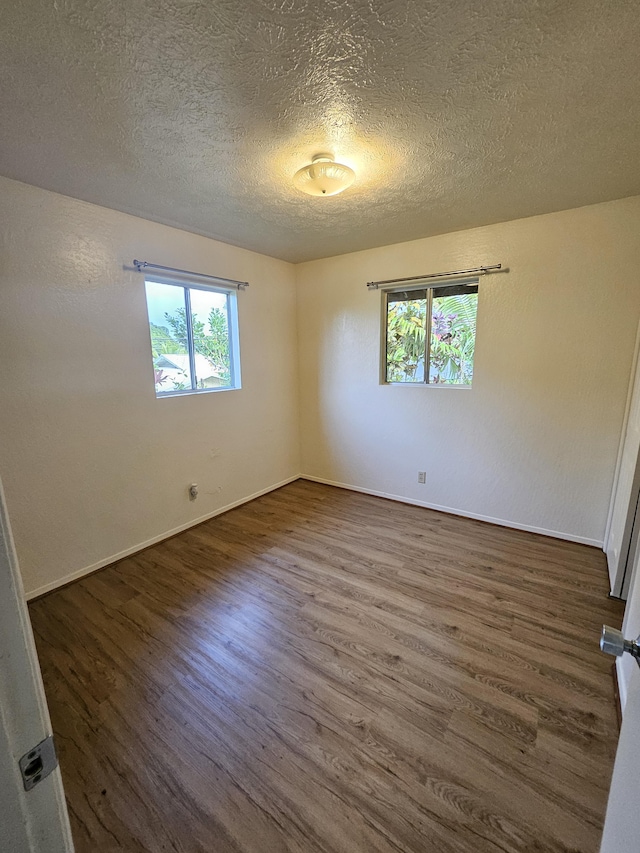 unfurnished room with dark wood-type flooring and a textured ceiling