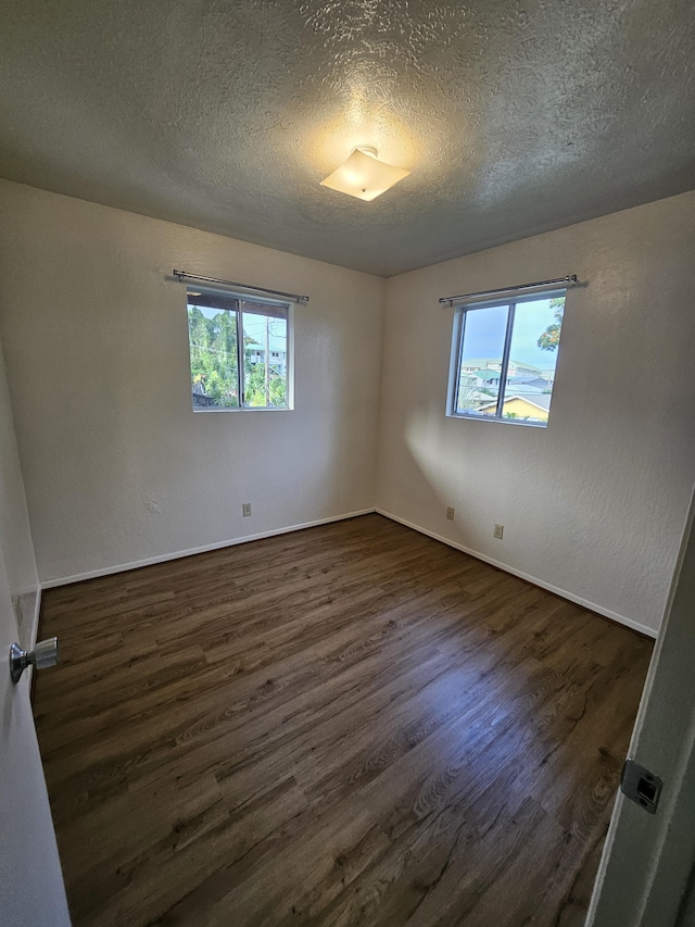 empty room with a textured ceiling and dark hardwood / wood-style flooring