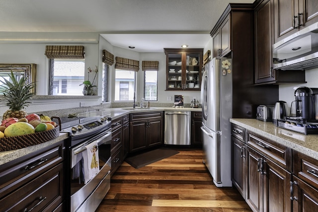 kitchen featuring appliances with stainless steel finishes, sink, dark hardwood / wood-style flooring, light stone counters, and dark brown cabinets