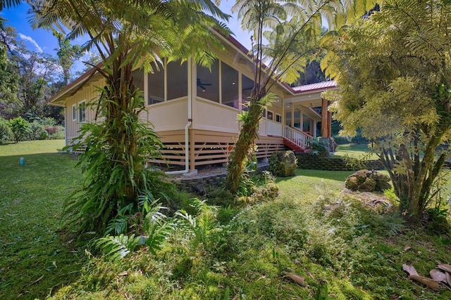 rear view of house with ceiling fan, a yard, and a sunroom