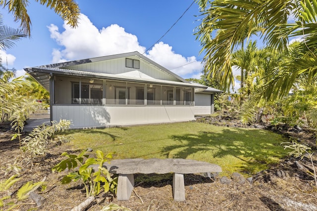 rear view of property featuring a sunroom and a yard