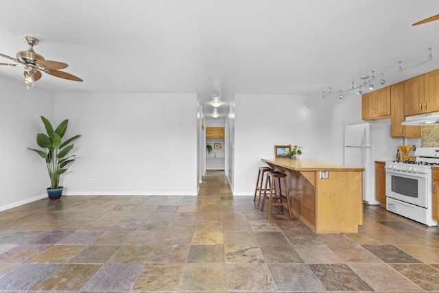 kitchen featuring a kitchen breakfast bar, rail lighting, white appliances, and ceiling fan