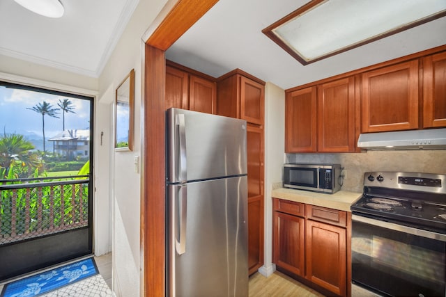 kitchen featuring stainless steel appliances, crown molding, and tasteful backsplash