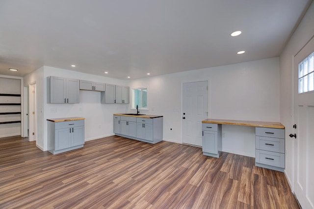 kitchen featuring dark hardwood / wood-style floors, gray cabinets, butcher block counters, and built in desk