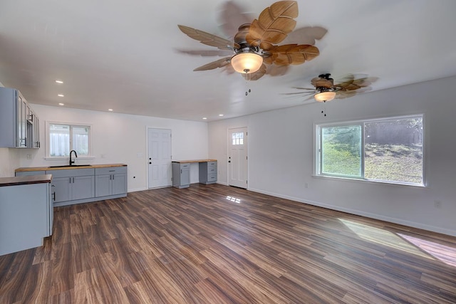 unfurnished living room featuring dark wood-type flooring, plenty of natural light, and sink