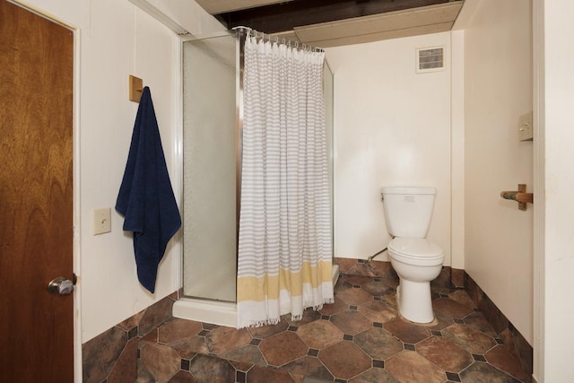 bathroom featuring toilet and curtained shower