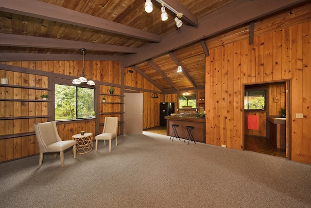 sitting room featuring lofted ceiling with beams, track lighting, dark carpet, and wood walls