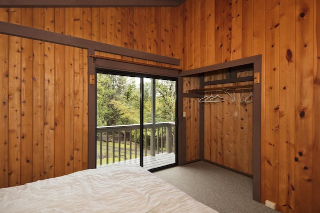 bedroom with access to exterior, a closet, wood walls, and carpet