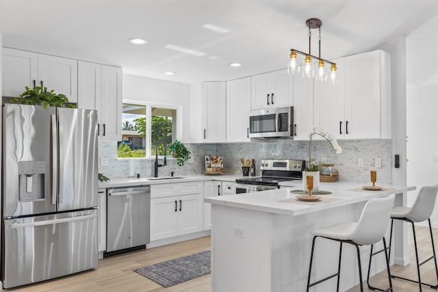 kitchen with white cabinetry, appliances with stainless steel finishes, sink, and decorative light fixtures