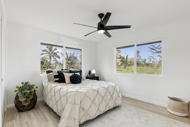 bedroom featuring ceiling fan, multiple windows, and light wood-type flooring