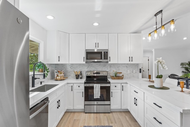 kitchen with white cabinetry, stainless steel appliances, kitchen peninsula, and sink