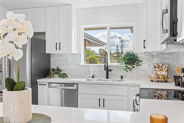 kitchen with sink, backsplash, white cabinets, and appliances with stainless steel finishes