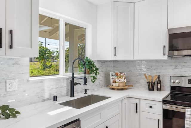 kitchen featuring white cabinetry, appliances with stainless steel finishes, sink, and light stone counters