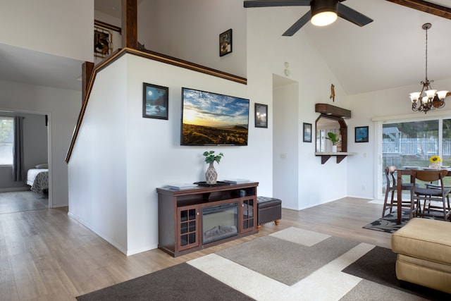 living room with high vaulted ceiling, beamed ceiling, ceiling fan with notable chandelier, and hardwood / wood-style flooring