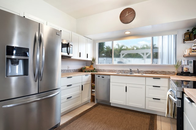 kitchen featuring white cabinets, butcher block counters, appliances with stainless steel finishes, and sink