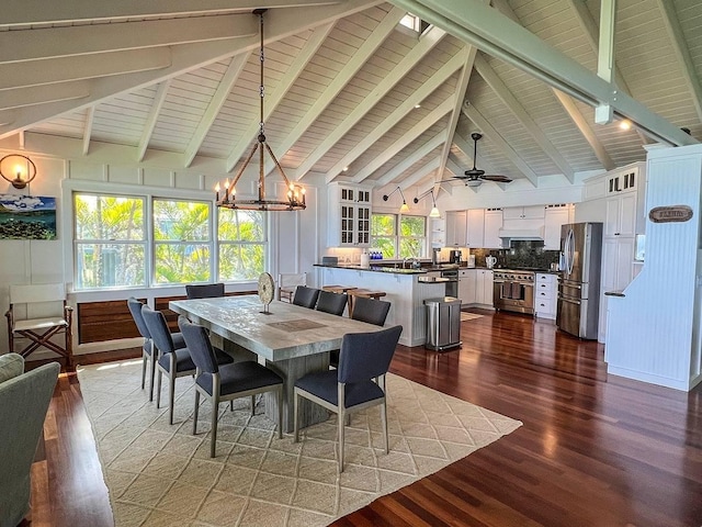 dining space featuring dark hardwood / wood-style flooring, beamed ceiling, high vaulted ceiling, and ceiling fan with notable chandelier