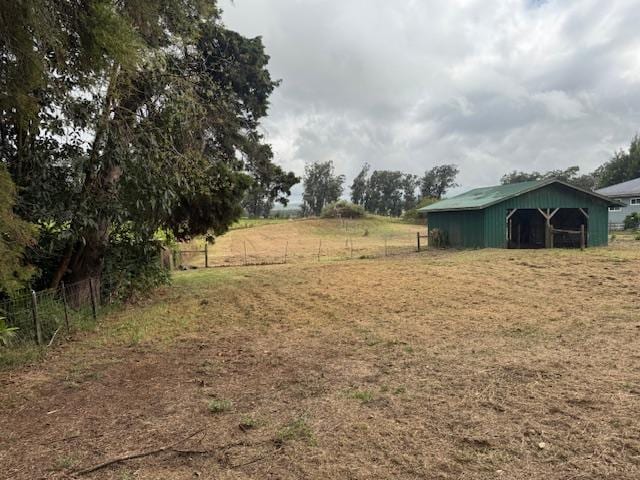 view of yard with a rural view, fence, an outbuilding, and an outdoor structure