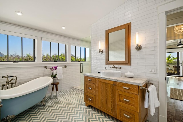 bathroom featuring vanity, tile walls, and a tub to relax in