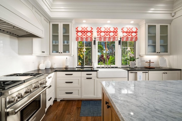 kitchen with premium range hood, stainless steel range, white cabinetry, and dark stone countertops