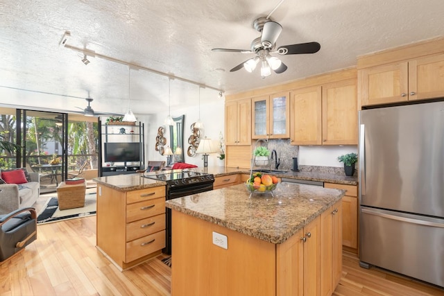 kitchen featuring pendant lighting, stainless steel fridge, a center island, light stone countertops, and light wood-type flooring