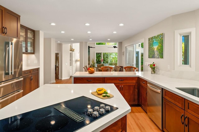 kitchen with appliances with stainless steel finishes, light hardwood / wood-style flooring, and kitchen peninsula