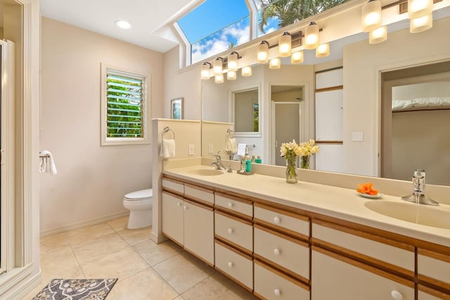 bathroom featuring toilet, a skylight, tile patterned floors, an enclosed shower, and vanity