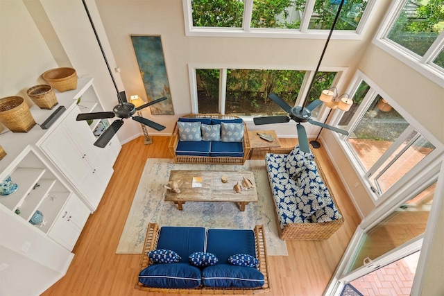 interior space with ceiling fan, a wealth of natural light, a high ceiling, and hardwood / wood-style flooring