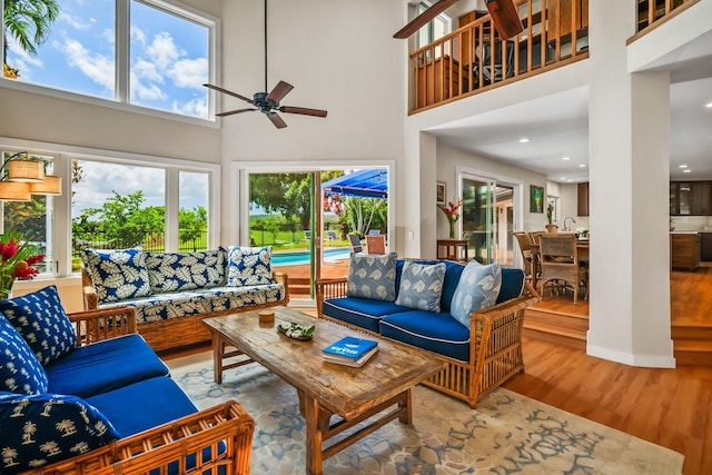 living room featuring ceiling fan, a towering ceiling, and hardwood / wood-style floors