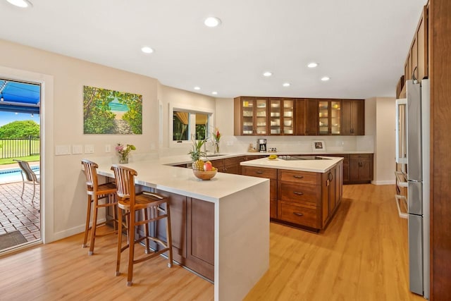 kitchen with light hardwood / wood-style floors, a breakfast bar, kitchen peninsula, and a healthy amount of sunlight