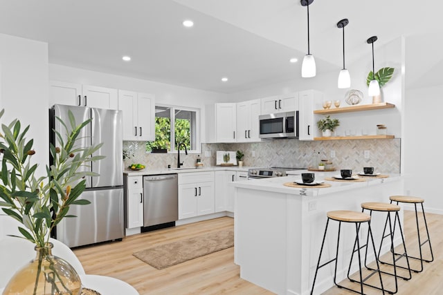 kitchen with a breakfast bar, light wood finished floors, stainless steel appliances, and light countertops