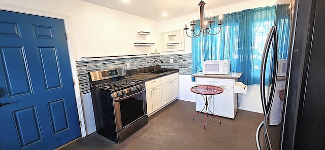 kitchen with sink, stainless steel gas range oven, decorative light fixtures, black refrigerator, and white cabinets