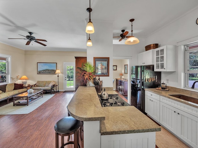 kitchen with white cabinetry, pendant lighting, a kitchen bar, and black appliances