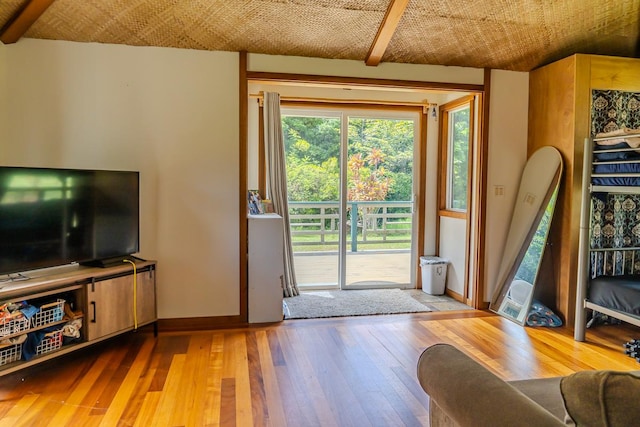 doorway to outside with beam ceiling and light wood-type flooring