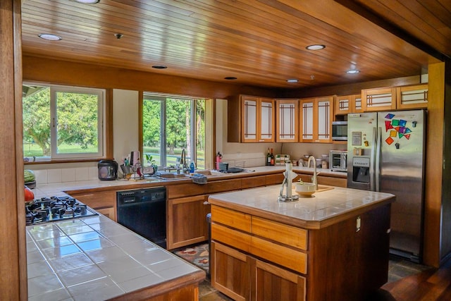 kitchen featuring stainless steel appliances, a center island, and tile countertops