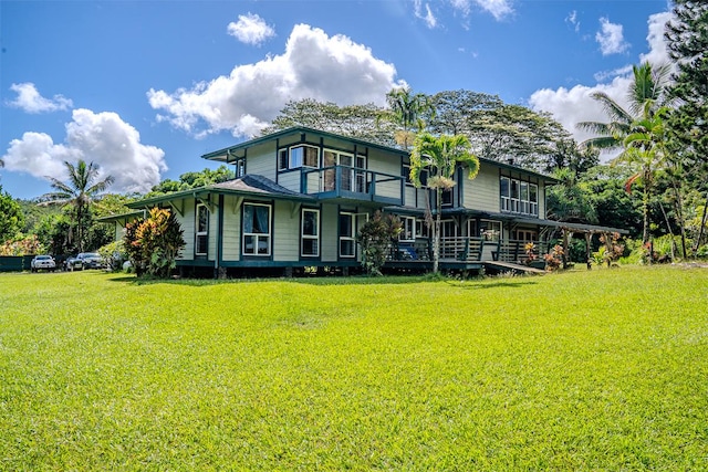 back of house featuring a balcony and a yard