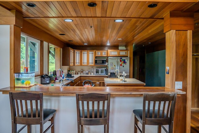 kitchen featuring sink, wooden ceiling, a breakfast bar area, and appliances with stainless steel finishes