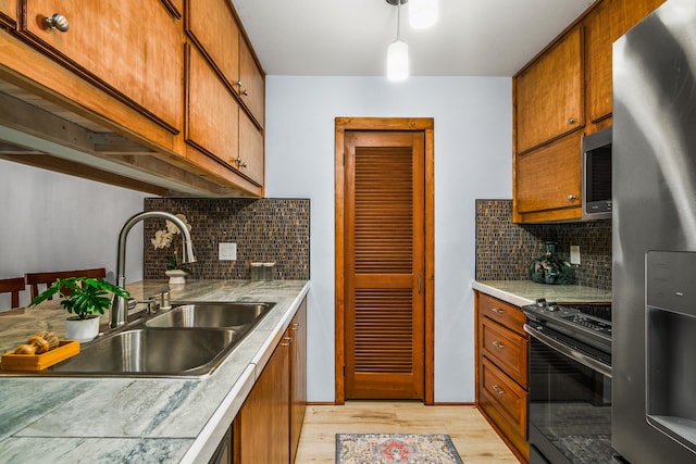 kitchen featuring light hardwood / wood-style floors, stainless steel appliances, backsplash, pendant lighting, and sink