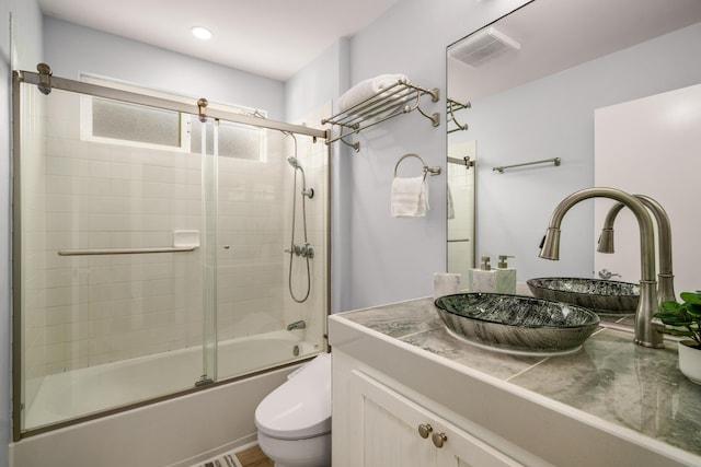 full bathroom featuring enclosed tub / shower combo, vanity, and toilet